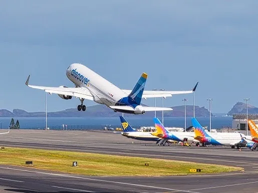 A plane taking off from the runway in Madeira, the ocean and islands behind it