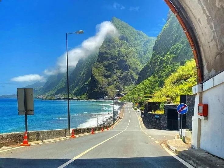 A coastal road emerging from a tunnel beside the Atlantic in Madeira