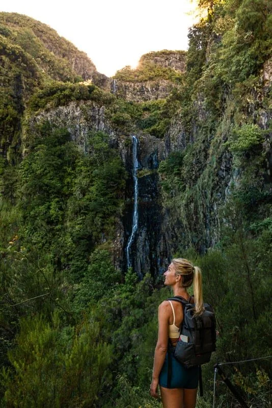 A woman beside a waterfall on a levada trail in Madeira